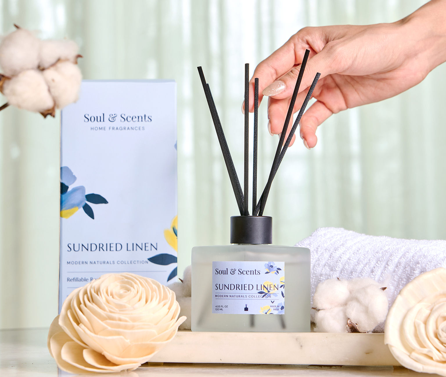 Scented diffuser with 'Soul & Scents' packaging on a wooden tray with cotton flowers.