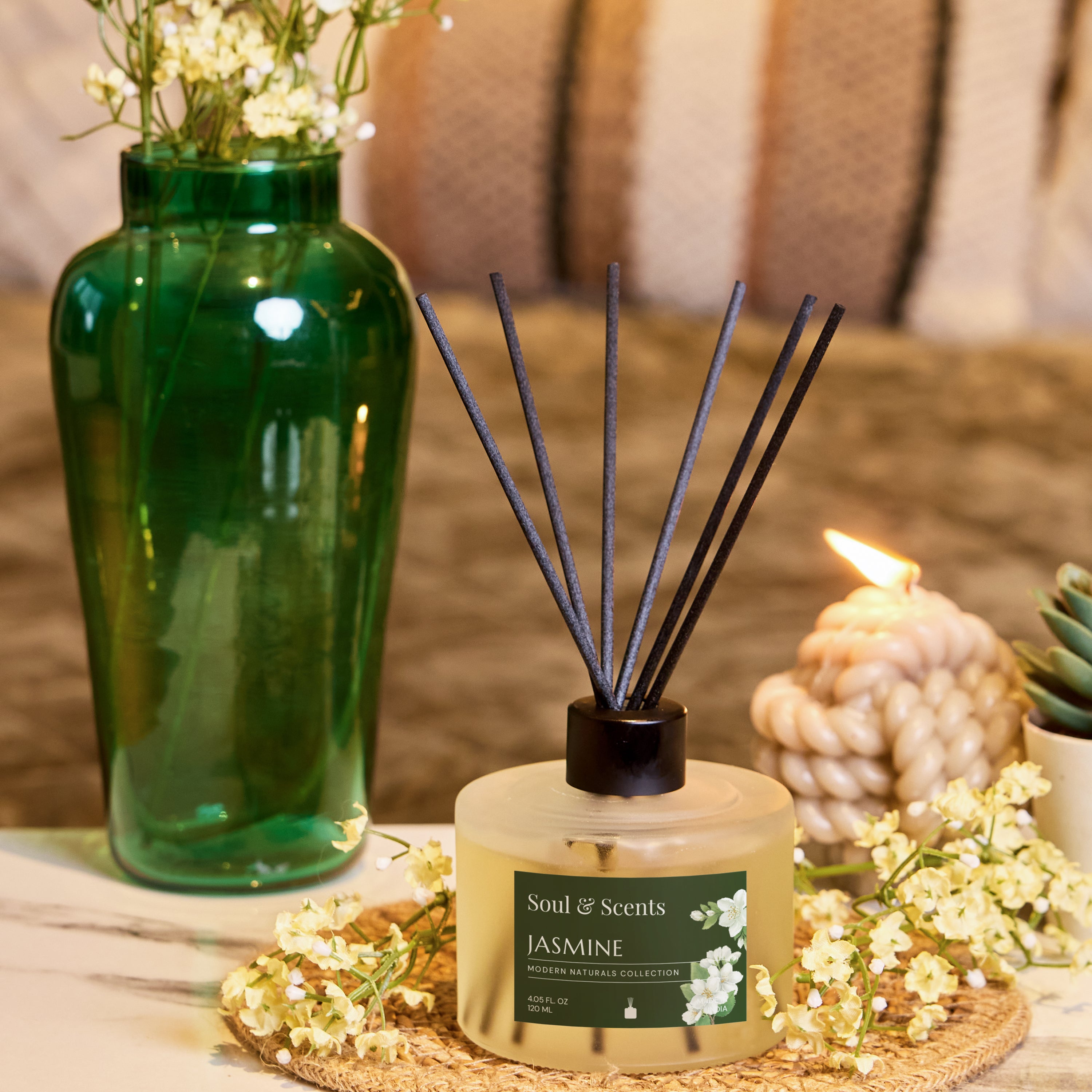 Scented diffuser with jasmine fragrance on a table with decorative elements.