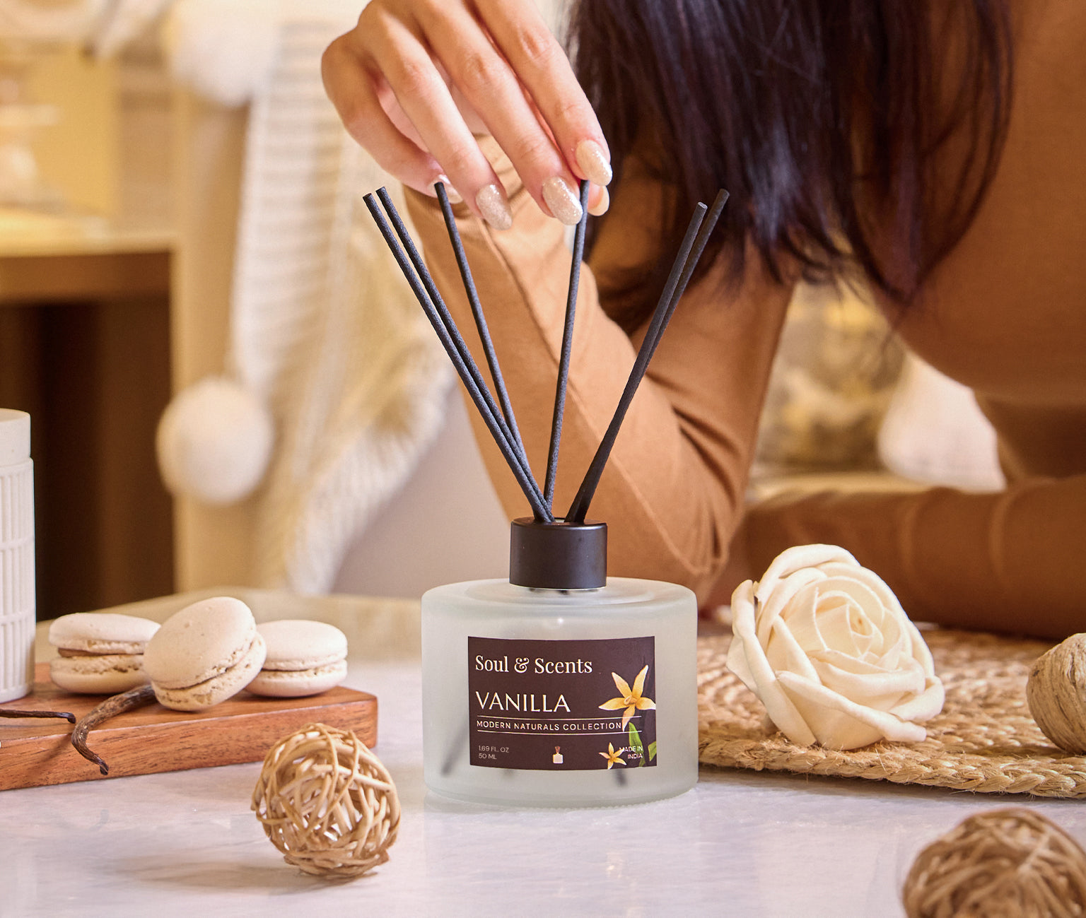 Person using a vanilla-scented diffuser with decorative elements on a table.