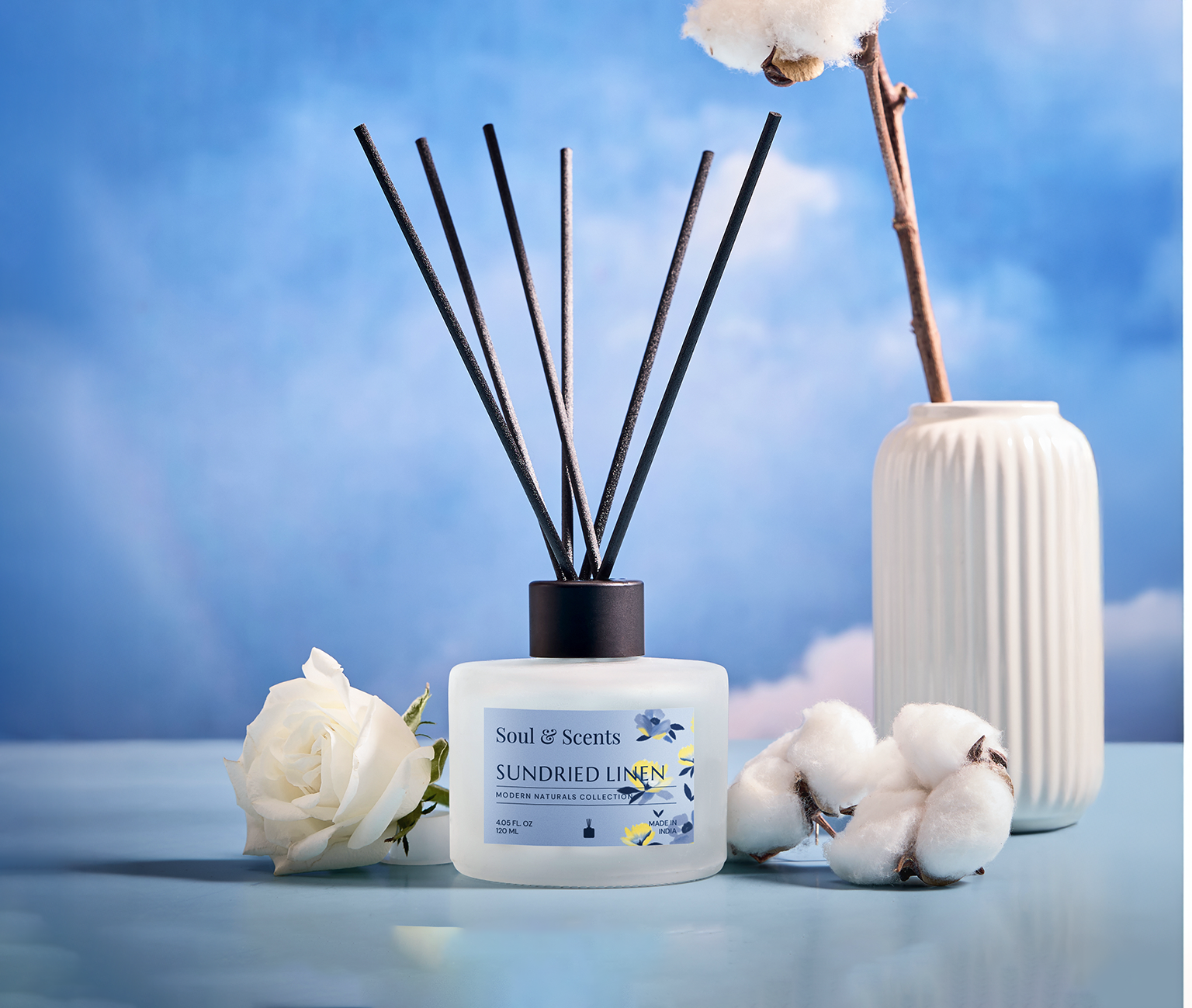 Scented diffuser bottle with reeds and decorative elements on a blue background