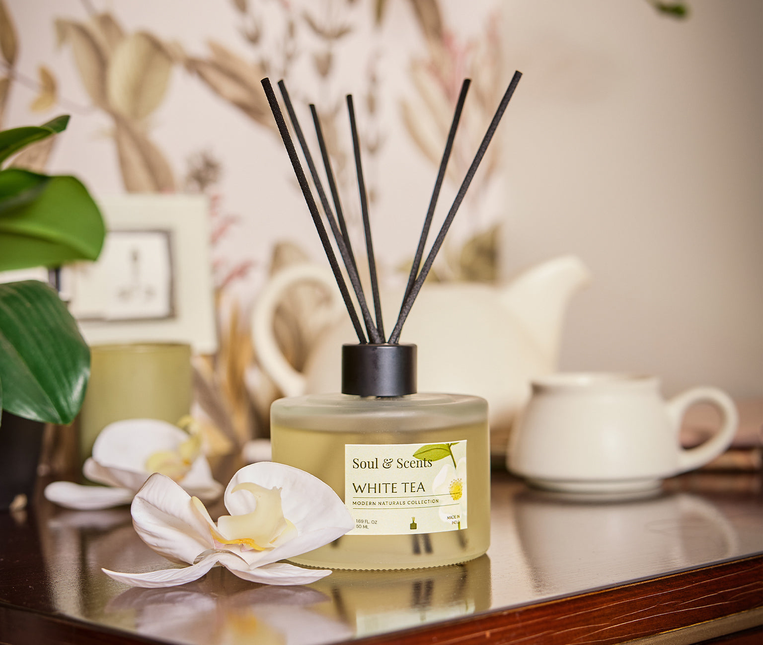 Scented diffuser labeled 'White Tea' by 'Soul & Scents' on a reflective surface with decorative elements.